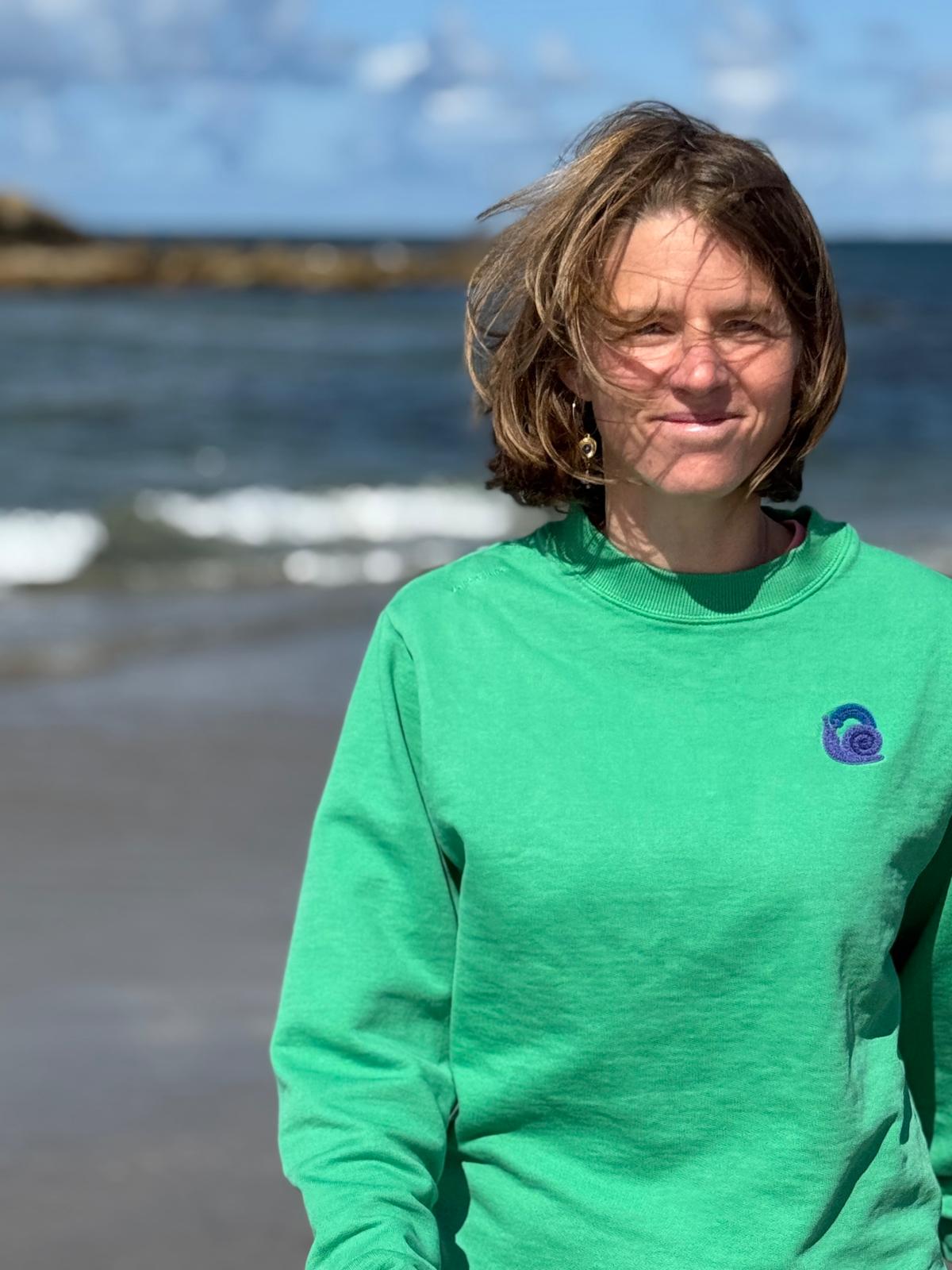 Celine standing by the sea wearing a Yellow June green sweater